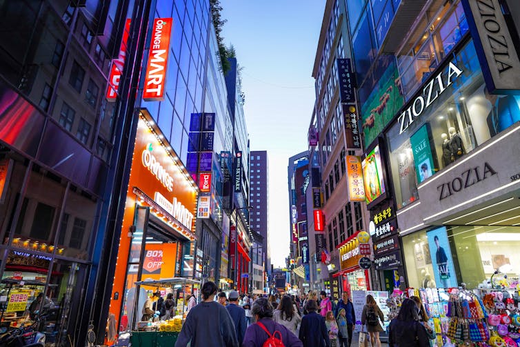 People walking in the street surrounded by billboards and lights in Seoul, South Korea