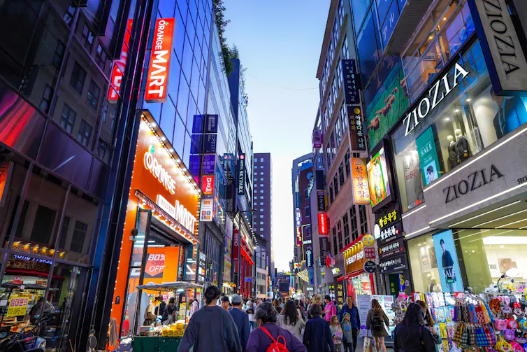 People walking in the street surrounded by billboards and lights in Seoul, South Korea