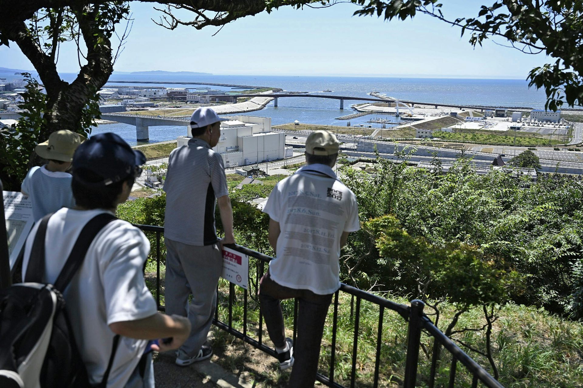 four people look at city and sea from high vantage point