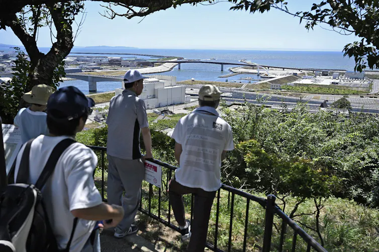 four people look at city and sea from high vantage point