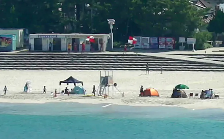 tents at the shoreline with people waving flags in background