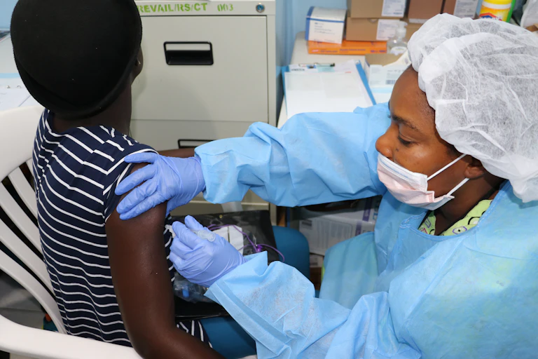 A health worker vaccinates a volunteer on the upper arm.