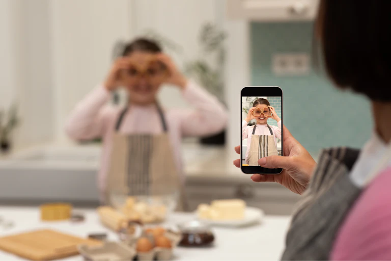 Una mujer hace una foto a una niña mientras cocina