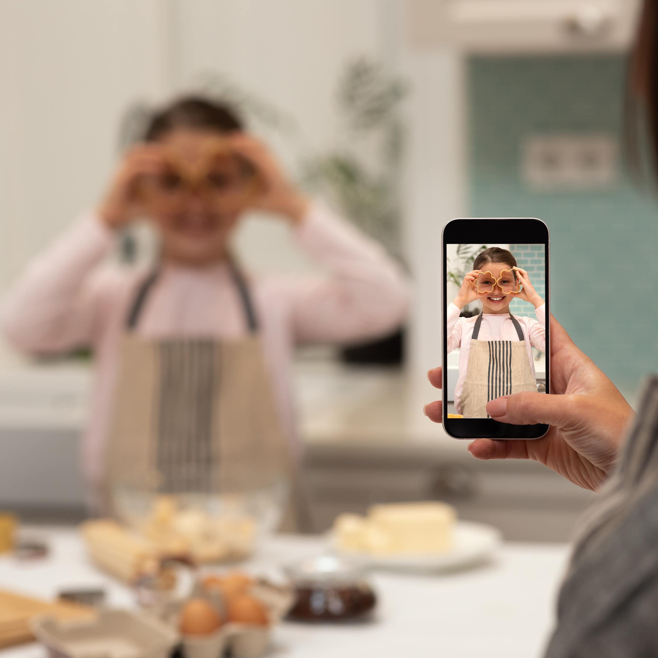 Una mujer hace una foto a una niña mientras cocina