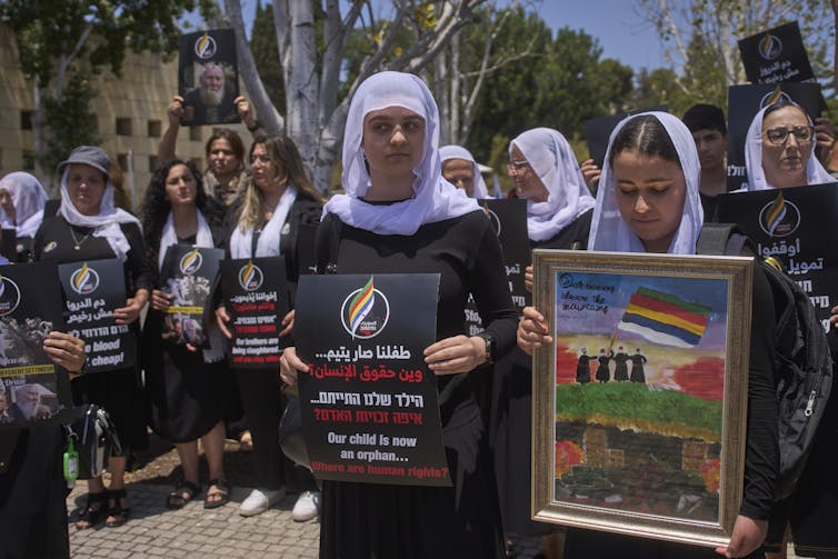 Las mujeres con cabezas con cabezas sostienen pancartas en una protesta.