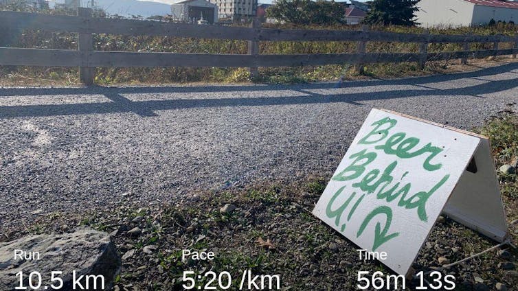 Image of a road with running stats along the bottom and a hand-lettered sign reading 'Beer Behind U!'