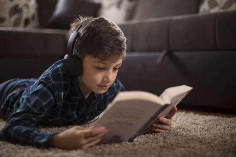 Menino lendo e ouvindo fones de ouvido