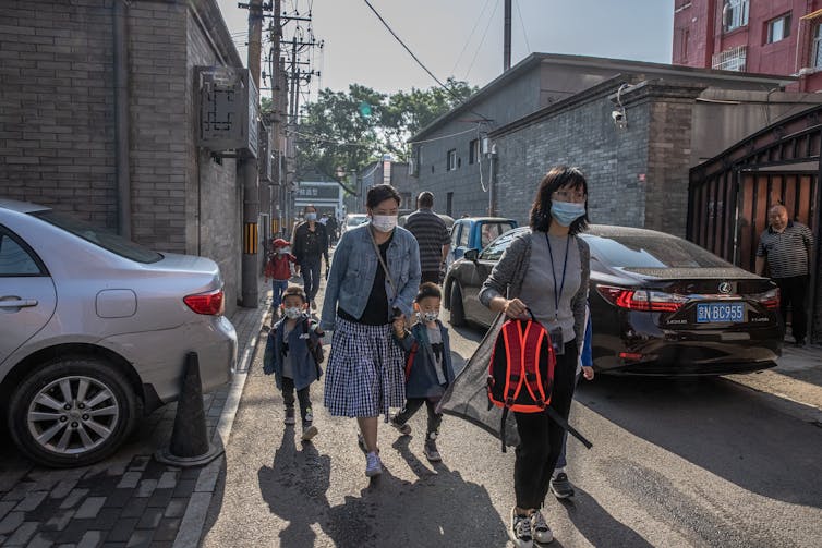 Parents walk their children to a kindergarten in Beijing.