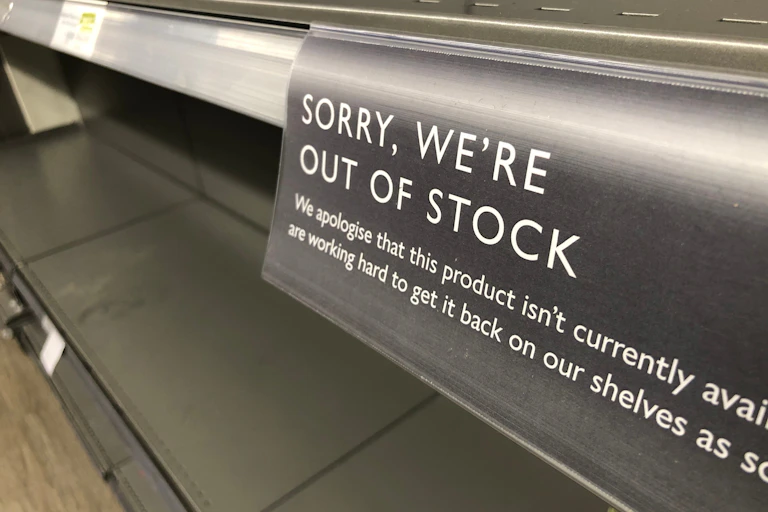 empty supermarket shelf bearing a sign saying sorry we're out of stock