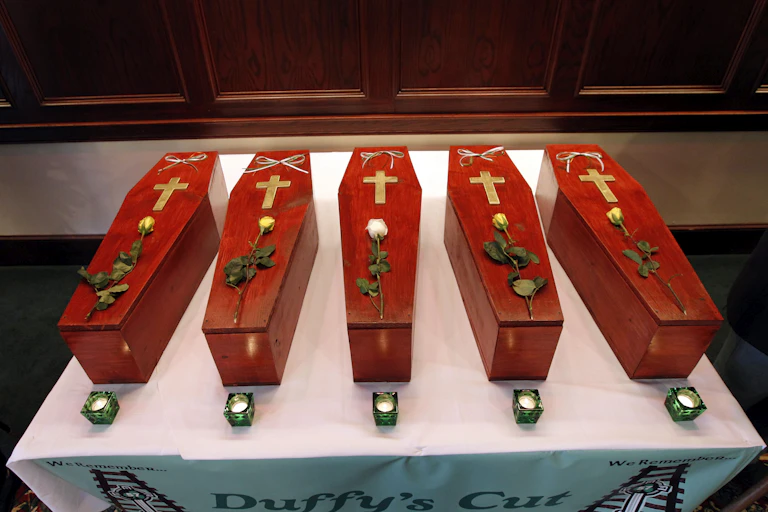 Row of five small red caskets with a cross and rose on top of each