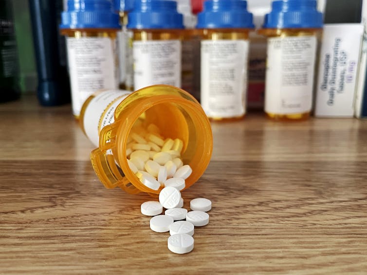 Antidepressants – white pills spilling out of a pill bottle onto wooden table