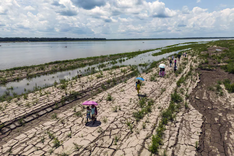 People walk on a dried, cracked riverbed