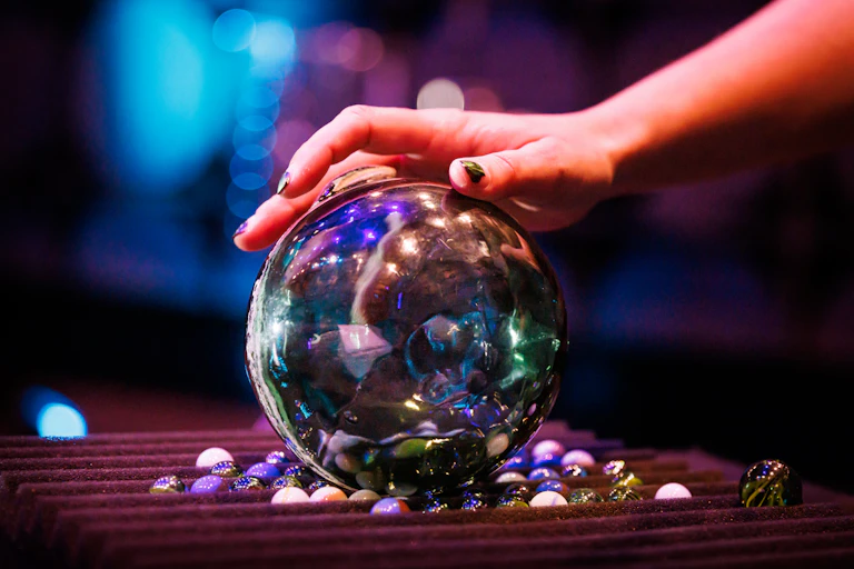 A hand rests on a glass fishing float.