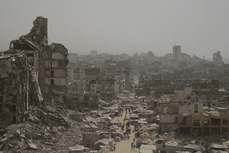 Bombed streetscape with collapsed buildings, rubble and tents
