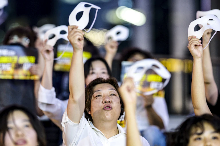 Women holding up masks and signs at a protest.