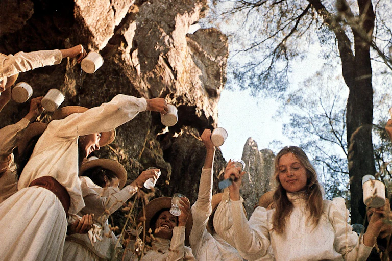 Film still: the girls raise cups in a toast.