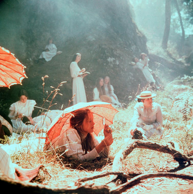 Film still: the girls lie in the grass.