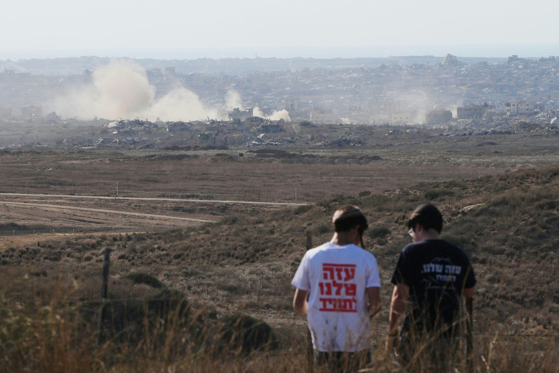 Two young Israeli men watch the devastation in Gaza. Their t-shirts read: 'Gaza is ours forever'.