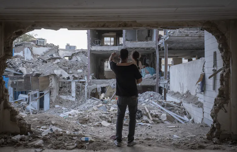 A man holds his child amid bombed-out rubble.