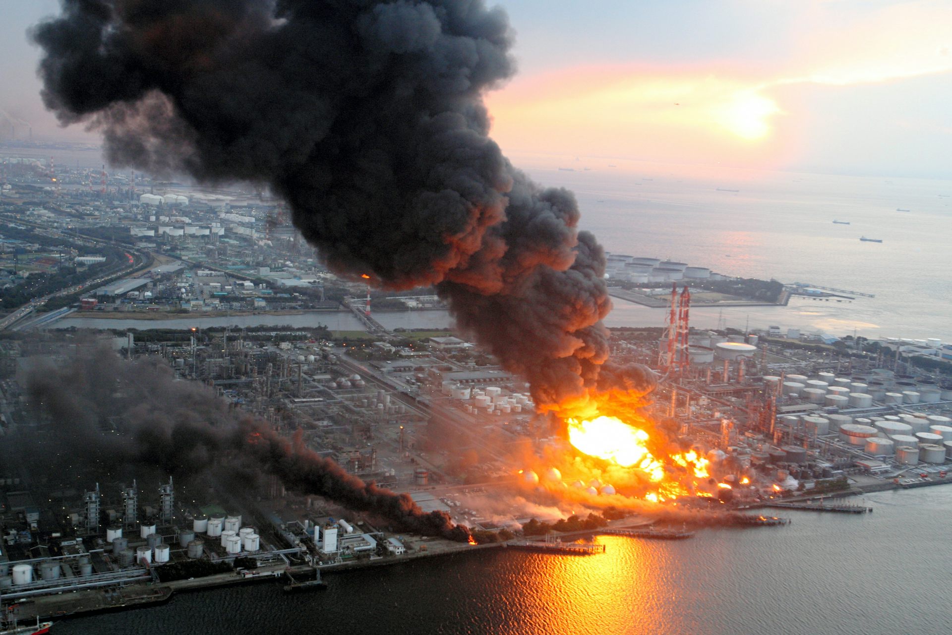An aerial view of a burning oil refinery at the coast.