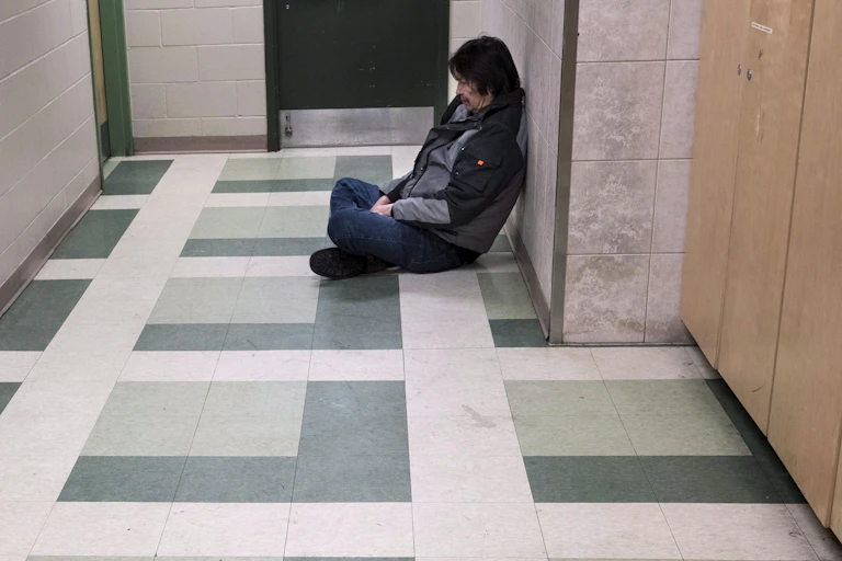 a man sits on the floor in a corridor