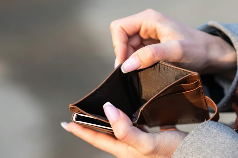 A person reaching into an empty wallet.