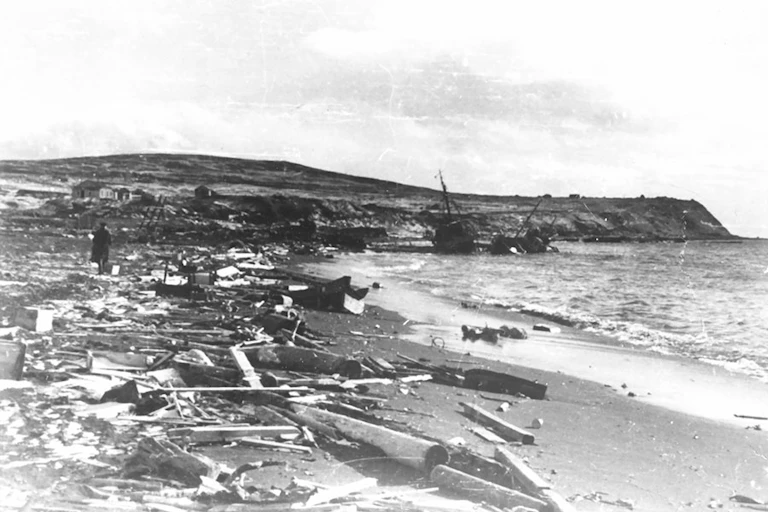 Black and white photo of destroyed buildings along a coast