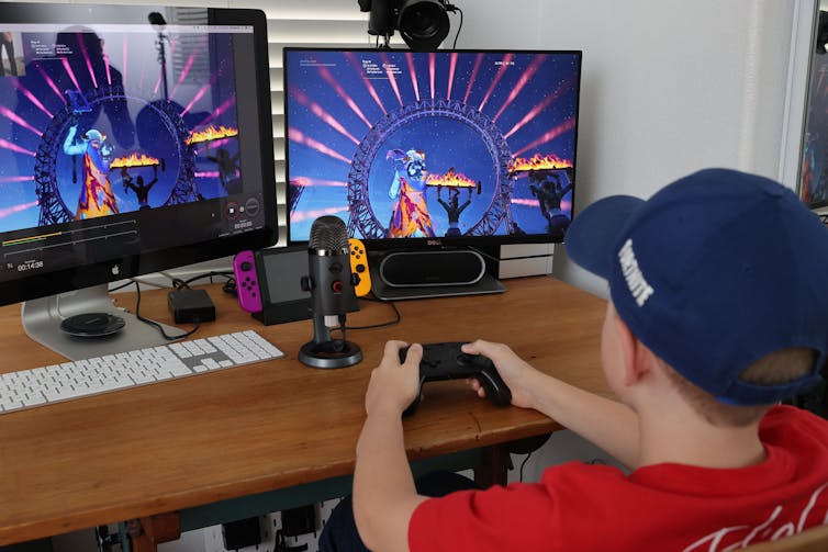 A tween boy plays a videogame with two screens.
