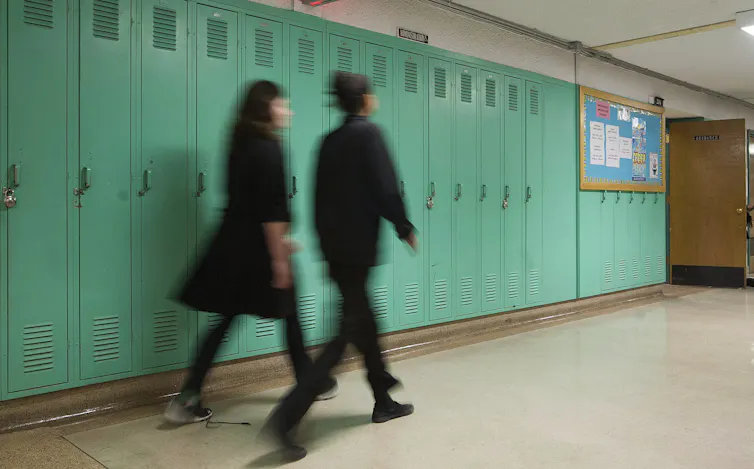 Two students blurred pass through a school hall.