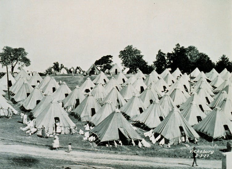 Rows of tents with people sitting in front of them.