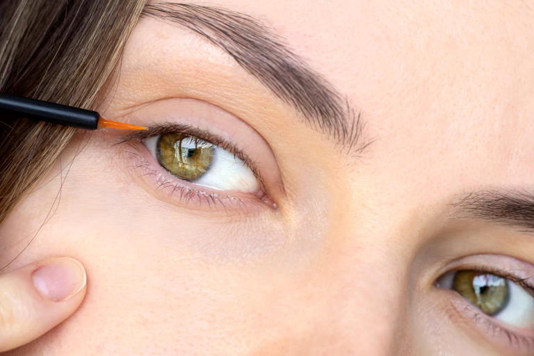 Close-up of woman applying lash growth serum to her eyelashes