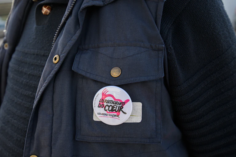 Un badge des Restaus du coeur sur l'anorak d'un bénévole