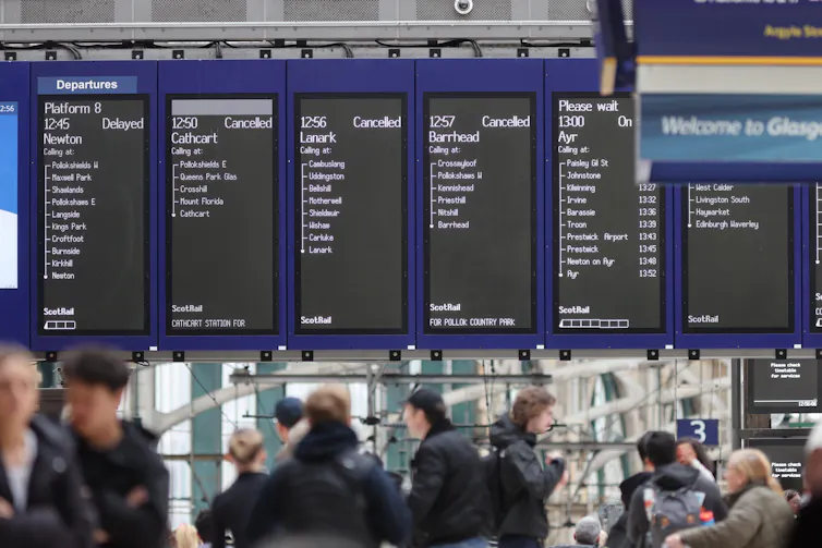 Departure boards above heads at a train station.