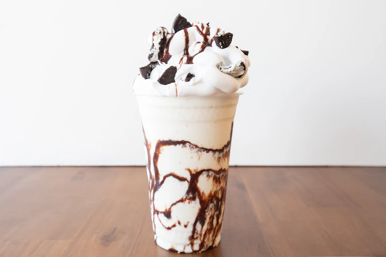 A large milkshake with chocolate syrup and whipped cream on top.