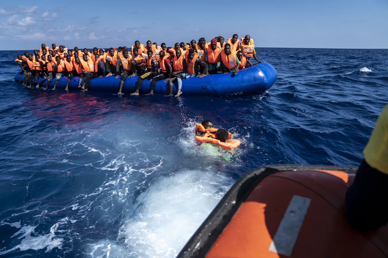 People wearing lifejackets crowded onto an inflatable boat