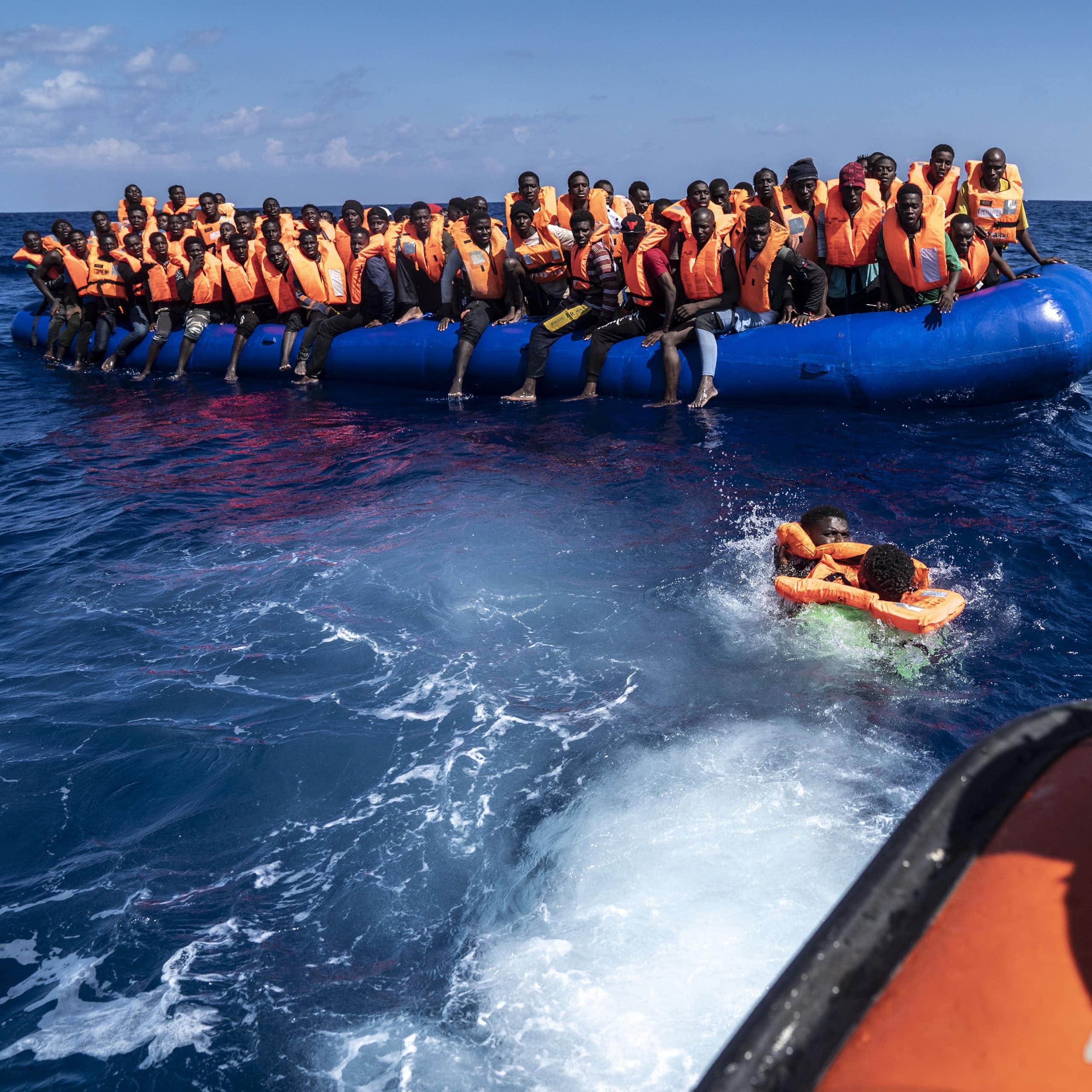 People wearing lifejackets crowded onto an inflatable boat