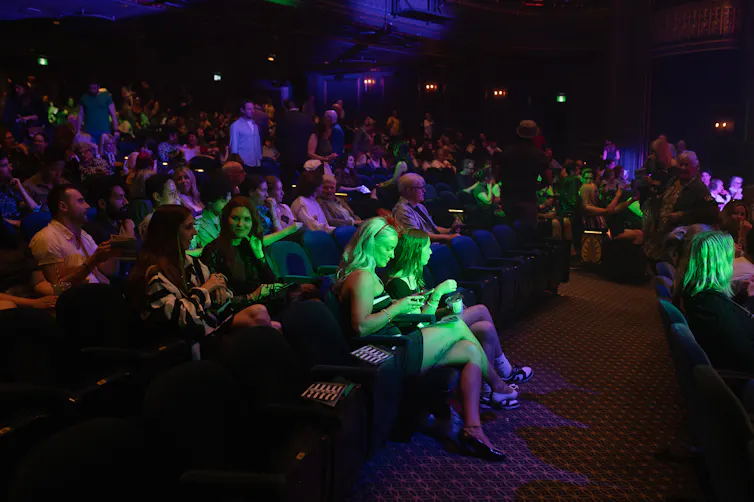 Miembros de la audiencia en la habitación oscura.