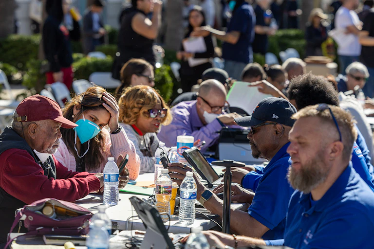 People who lost homes and businesses to the Los Angeles wildfires get help filling out forms from staff at a FEMA assistance center.