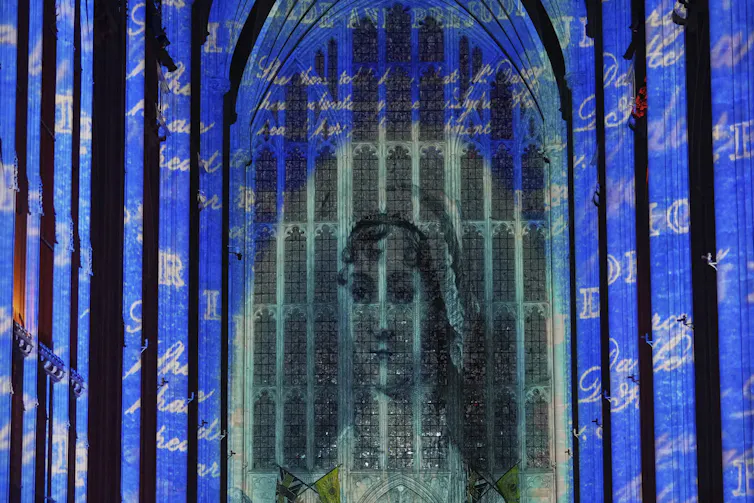 A projected image of a woman seen on church windows.