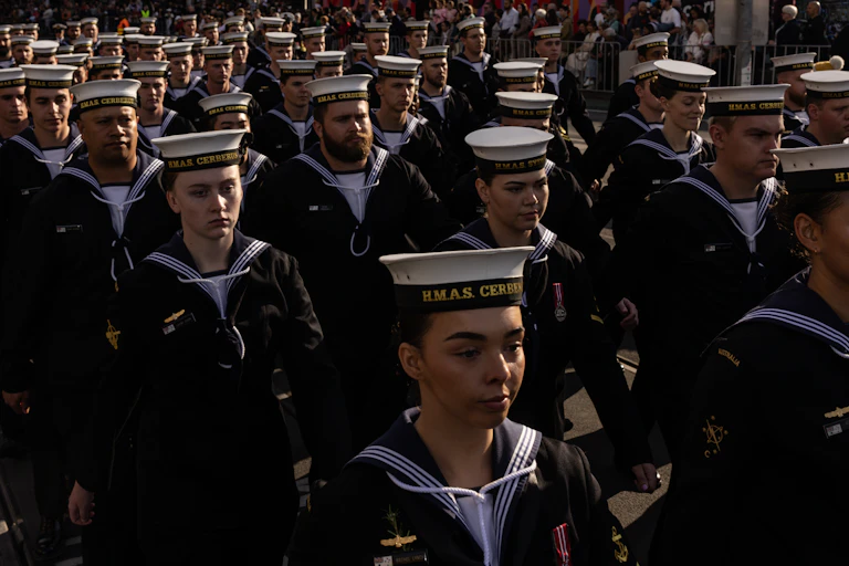 A crowd of Navy members march in full uniform