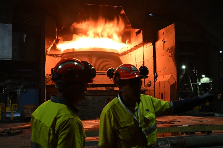 two people stand in front of industrial furnace