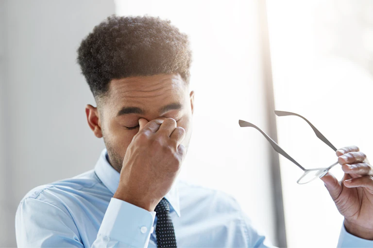 Man takes off glasses and rubs forehead
