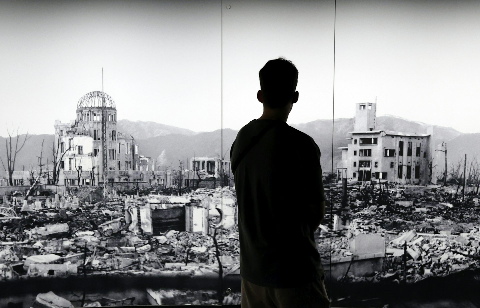 The silhouette of a man looking at a picture of Hiroshima devastated by the world's first atomic bombing.