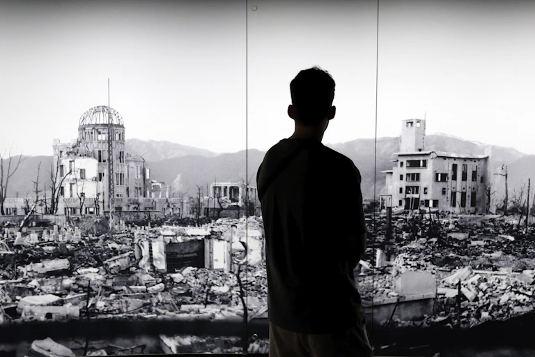 The silhouette of a man looking at a picture of Hiroshima devastated by the world's first atomic bombing.