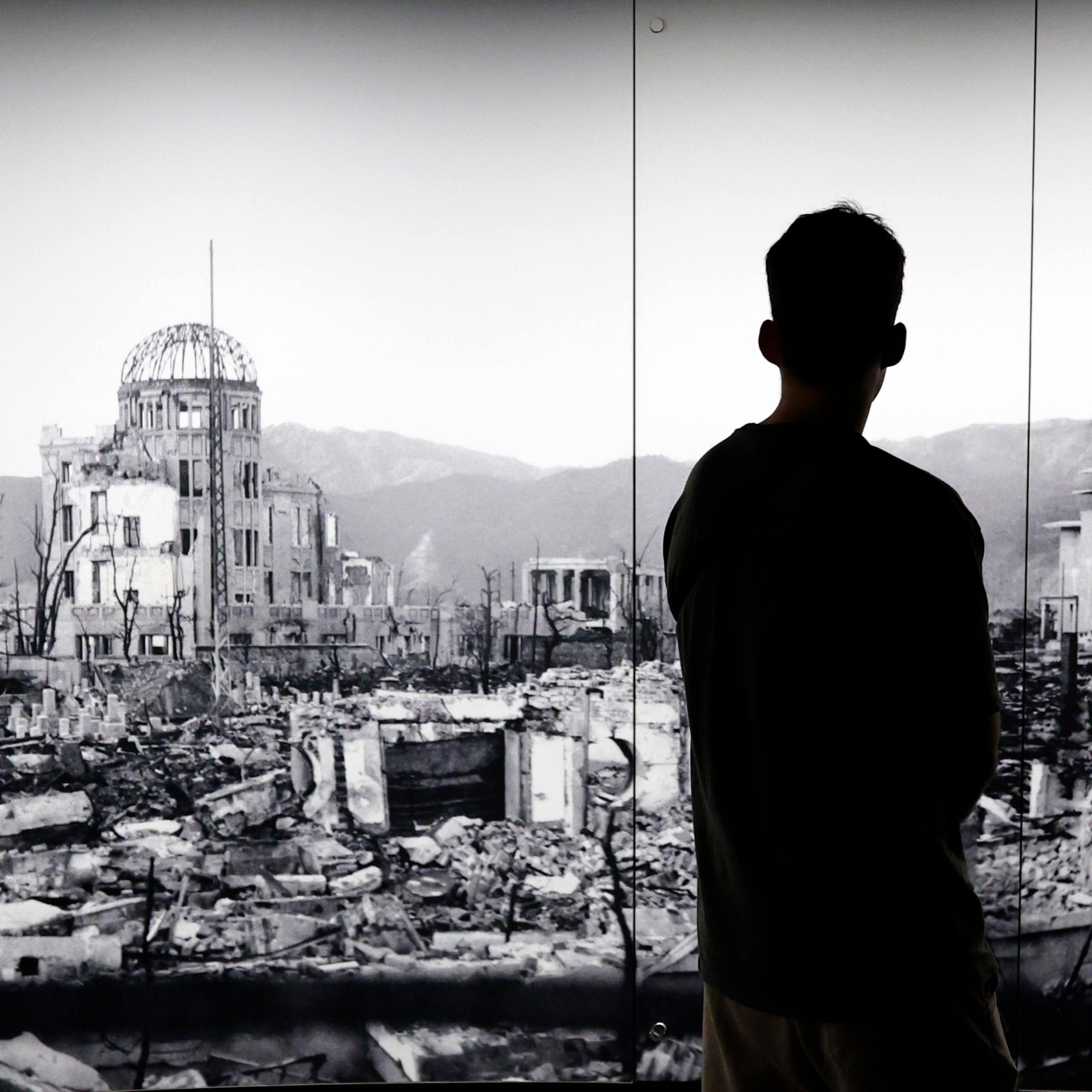 The silhouette of a man looking at a picture of Hiroshima devastated by the world's first atomic bombing.