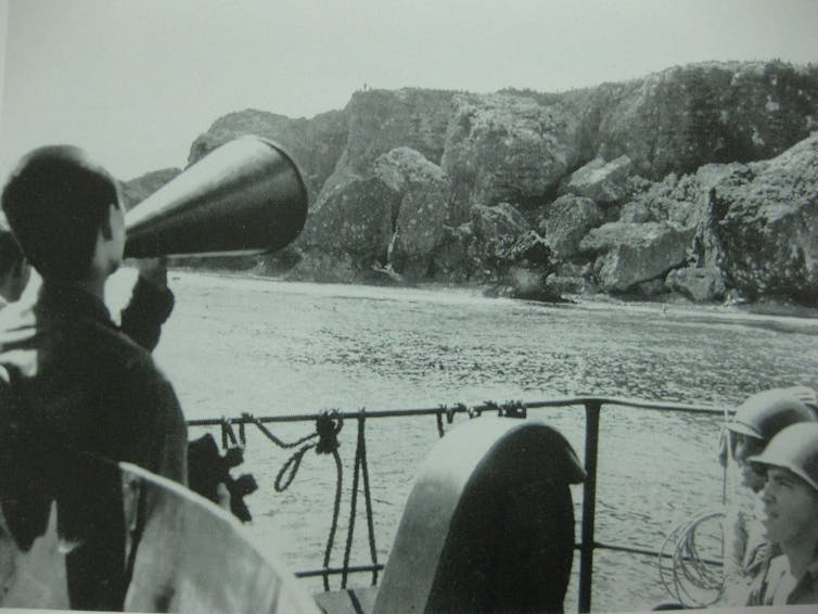 When US and Jap troops stopped preventing to speak, devour and pray in combination 1 Archival photograph of a Japanese POW shouting through a loudhailer from a ship to an island.