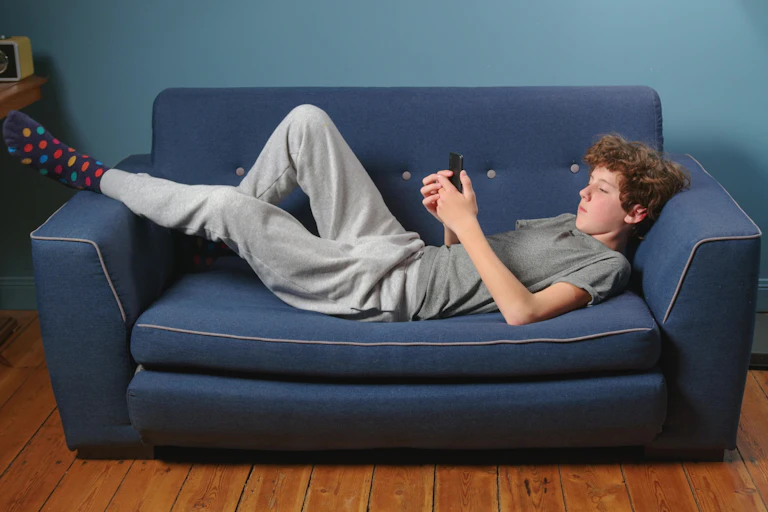 Boy on phone lying on sofa