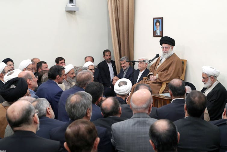 A group of men hold a meeting.