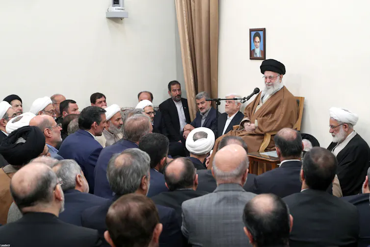 A group of men hold a meeting.