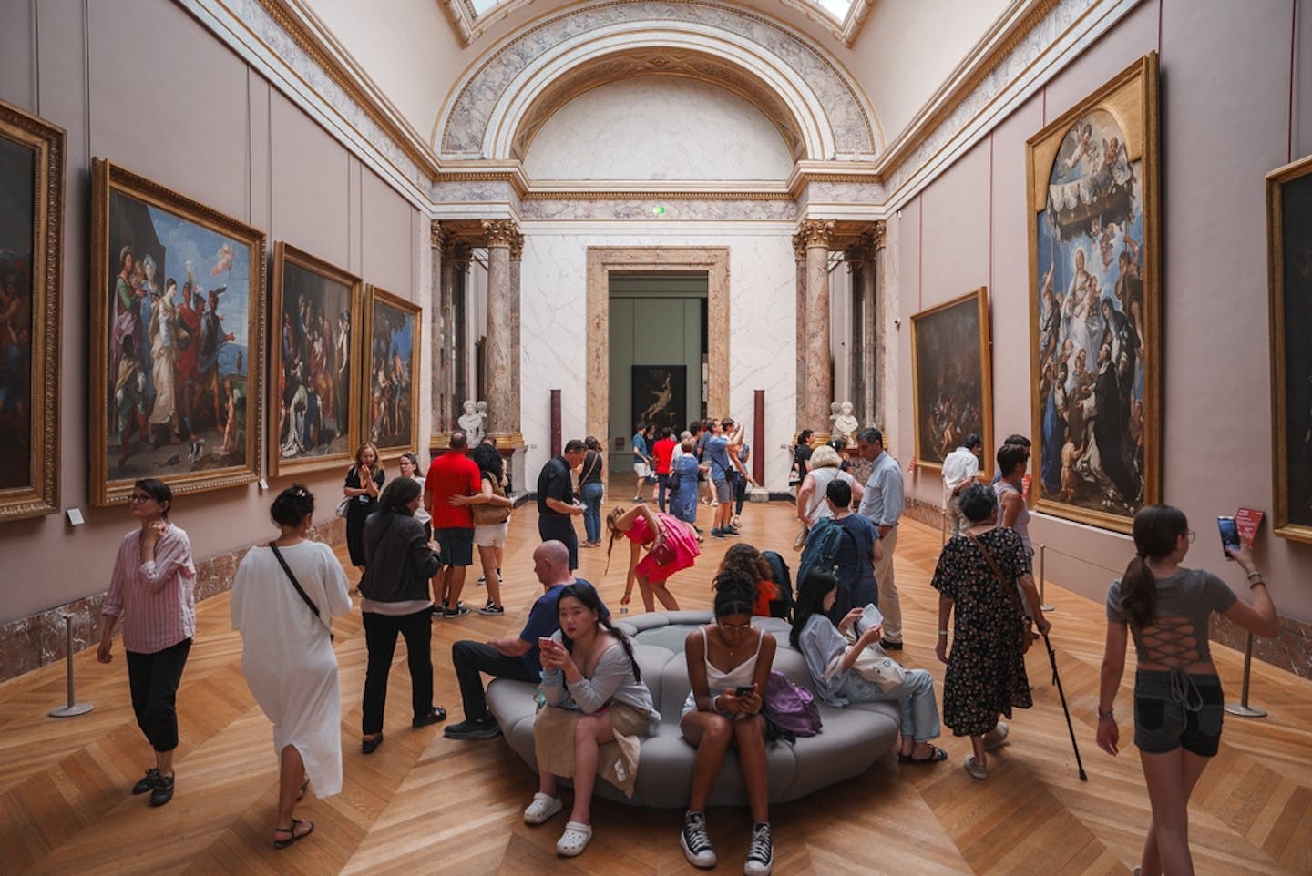 Visitantes en una sala con bastante gente dentro de un museo.